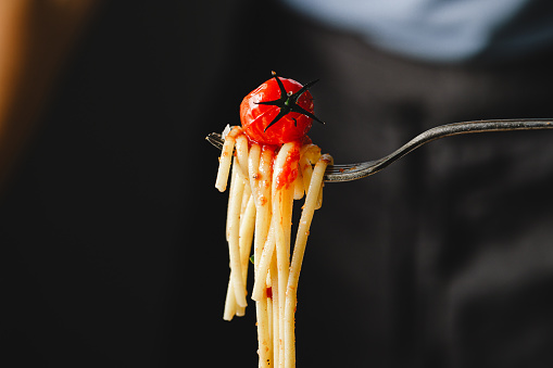 Close-up of fork with tomato pasta. Eating freshly made  pasta with fork.