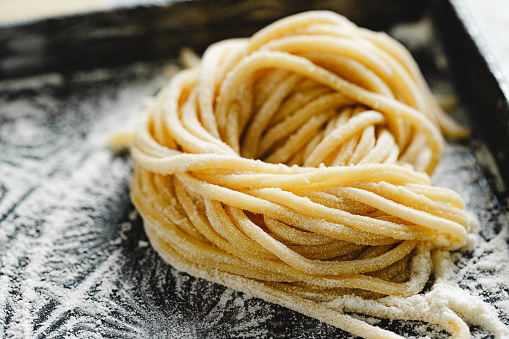 Close-up of homemade spaghetti on kitchen counter. Freshly prepared pasta with flour on the kitchen table.