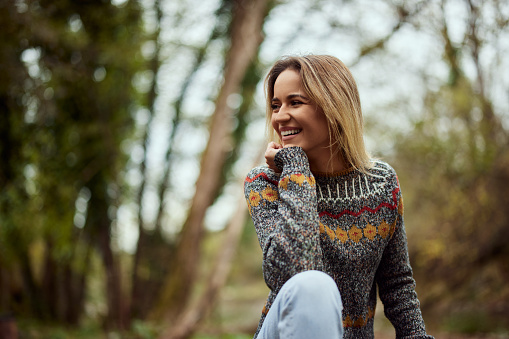 A beautiful blonde girl, smiling, being in nature, dressed casually.
