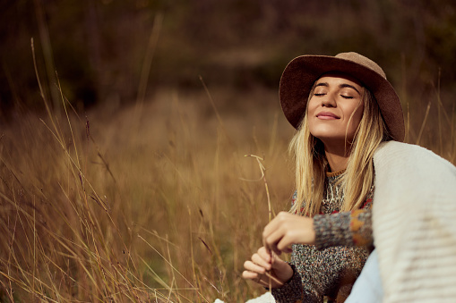 A beautiful woman sitting on the grass in the field, sitting by herself.