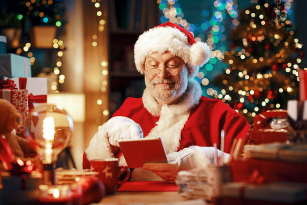istock Happy Santa Claus using a digital tablet at home 1803856924