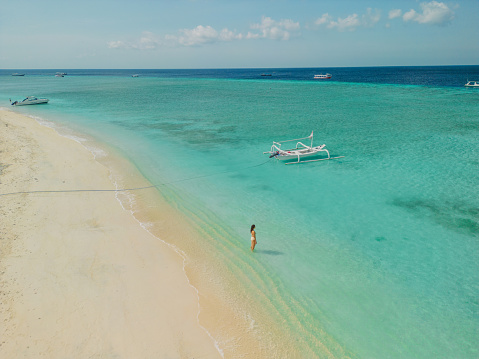 Aerial view of woman walking on idyllic tropical beach with white sand  on Gili Meno island