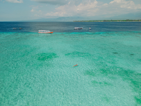 Aerial view of woman swimming near perfect Gili Meno island near the tour boat