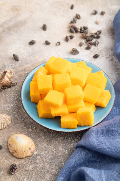 istock Dried mango cubes on blue plate on brown concrete, side view. 1803885150