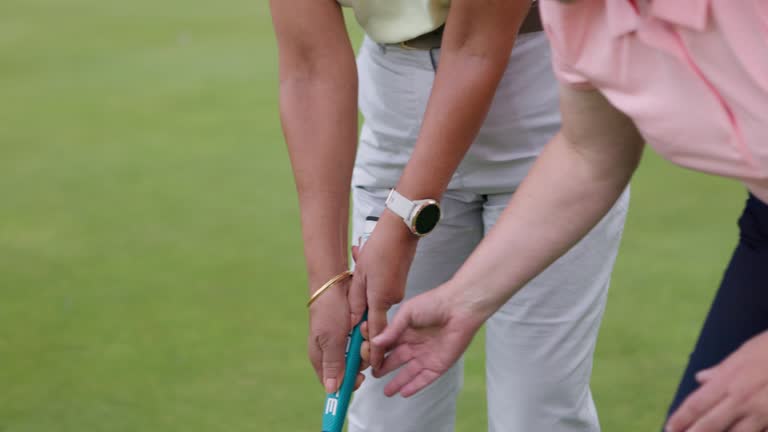 Woman, coach and sport training for golf on course for development in stroke or swing of club. Hands, closeup and personal trainer help player with stick, hit and balls on pitch in sports game