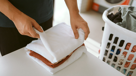 Man doing launder holding basket with dirty laundry of the washing machine in the public store laundry clothes