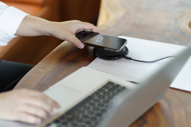istock Charging mobile phone battery with wireless charging device in the table. Smartphone charging on a charging pad. Mobile phone near wireless charger Modern lifestyle technology concept 1803928950