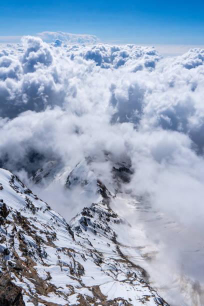 171114806 paisaje alpino con picos cubiertos de nieve y nubes montañas nubladas. montañas en nubes al amanecer en verano. vista aérea del pico de la montaña con árboles verdes en la niebla. vista superior del valle de la montaña en nubes bajas desde un dron. m