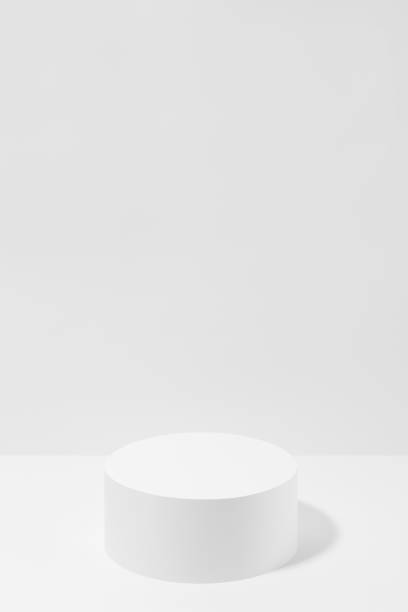 istock Abstract one white round podium for cosmetic products in hard light, mockup on white background, vertical. Scene for presentation products, gifts, goods, advertising, design, sale, display, showing. 1803935257