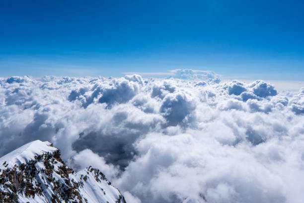 171114806 paisaje alpino con picos cubiertos de nieve y nubes montañas nubladas. montañas en nubes al amanecer en verano. vista aérea del pico de la montaña con árboles verdes en la niebla. vista superior del valle de la montaña en nubes bajas desde un dron. m
