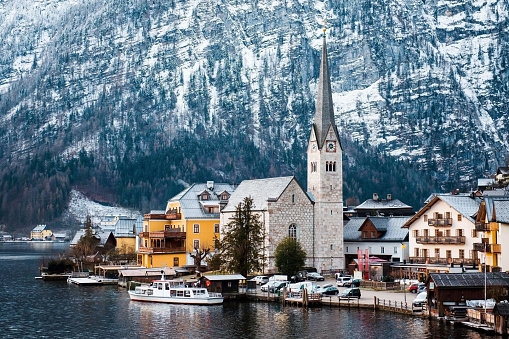 Amazing landscape of old austrian town with traditional houses near lake. High snowy Alps on background. Natural backdrop and wallpaper.