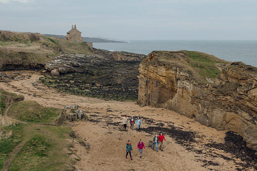 A super high wide angle view group of mature and senior women enjoying a day out in Bamburgh, North East England. They are enjoying a walk in the fresh air together while bonding. They are appreciating the quiet calm empty beach.