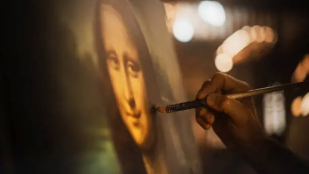 Photo of Close Up on Male Painter Hand Painting the Mona Lisa with Gentle Brush Movement. Details of the Famous Painting Being Drawn by its Creator. Pure Talent and Mastery of High Art, Everlasting Beauty