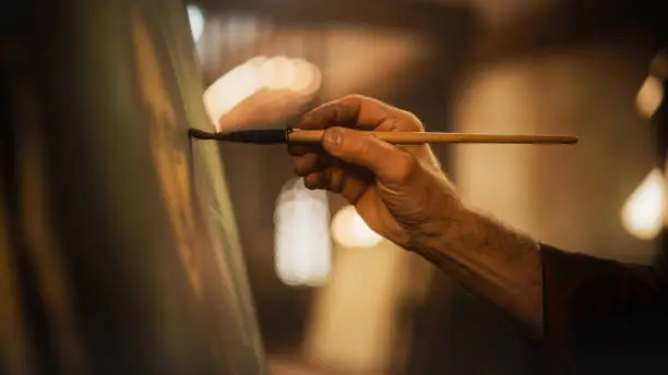 Photo of Close Up on Male Painter Hand Painting the Mona Lisa with Gentle Brush Movement. Details of the Famous Painting Being Drawn by its Creator. Pure Talent and Mastery of High Art, Everlasting Beauty