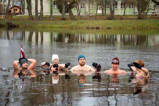 Preili, Latvia - November 18 2023: Group of people ice bathing together in the cold water of a lake in Preili, Latvia. Wim Hof Method, cold therapy, breathing techniques, yoga and meditation