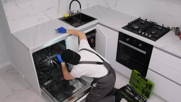 A man installs a new dishwasher in the kitchen room stock photo