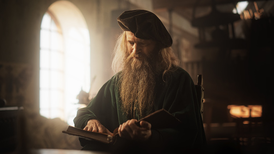 Portrait of Old Male Historical Figure Reading a Book then Looking at the Camera with a Smile. Friendly Renaissance Librarian Keeping Treasures of Knowledge and History Safe