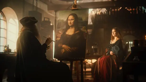 Photo of Recreation of Historical Moment: Beautiful Model Giving Life to the Painting of the Mona Lisa By Posing While the Painter Leonardo da Vinci is Making a Portrait of Her in Art Workshop. Renaissance Era