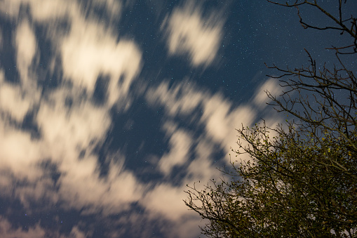 Blurred motion of stars and clouds in a night sky.