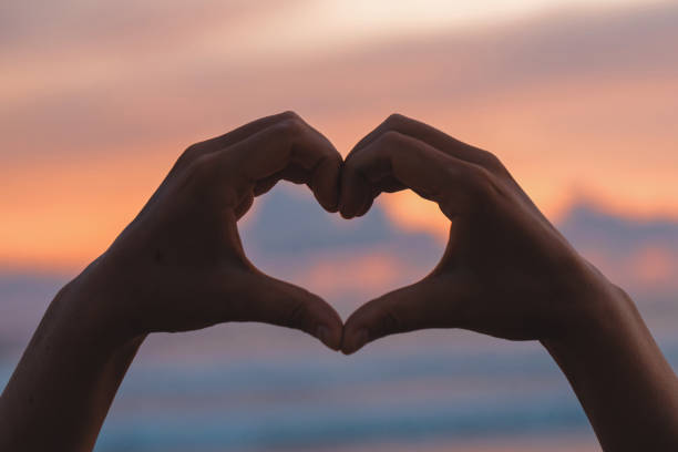 istock Hands forming a heart shape with sunset silhouette 1803989245
