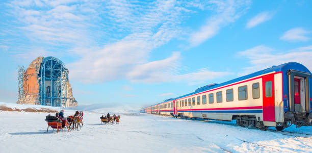istock Red diesel train (East express) in motion at the snow covered railway - Horses pulling sleigh in winter - Ani Ruins, Ani is a ruined and  medieval Armenian city - Kars, Turkey 1803989840
