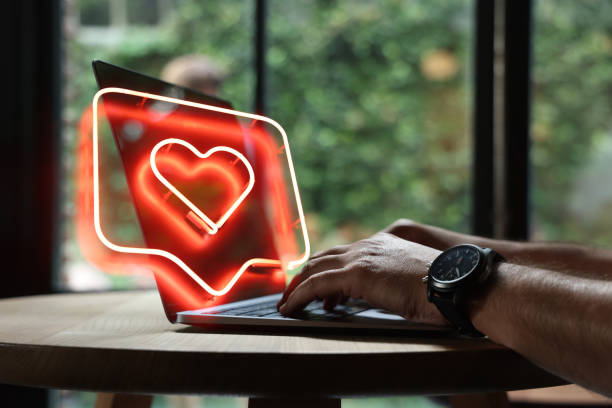 Uomo che usa il computer portatile con la forma del cuore - foto stock