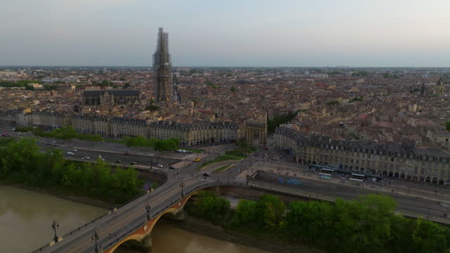 Establishing shot of the French city of Bordeaux. A drone flies over an ancient European city. Sunset in western France. Trams and tourists on bicycles crossing the Pont de Pierre bridge