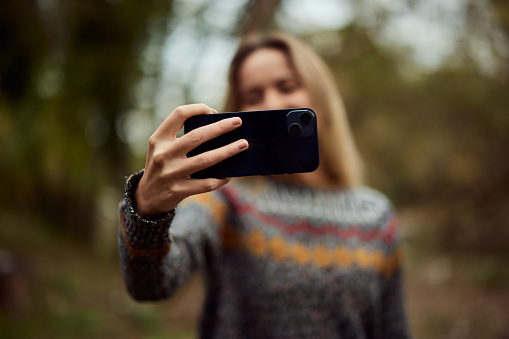 Close-up photo of a mobile phone, a girl taking photos of herself, in nature.