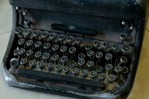 An antique, black, manual Hebrew typewriter in poor condition following years of use.