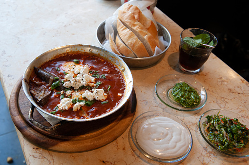 Shakshouka, popular in the Middle East and Israel, is a Maghrebi dish of eggs poached in a sauce of tomatoes, olive oil, peppers, onion and garlic, and served with fresh bread, tea and herbs.