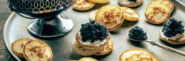 istock Blinis with black caviar panorama. Mini pancakes on a festive dish 1804007046