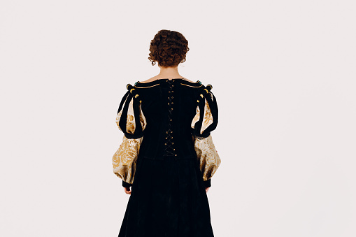 Portrait of a young aristocratic woman dressed in a medieval dress on white background. Back view