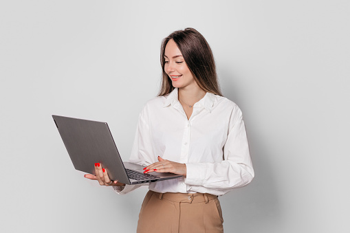 business woman with a laptop isolated on a white background. young woman marketer working with laptop while standing