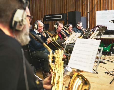 Music, band and instrument with people in a recording studio, reading sheet music for a performance. Concert, jazz and musician group playing as an orchestra for art, creative or sound at a showcase