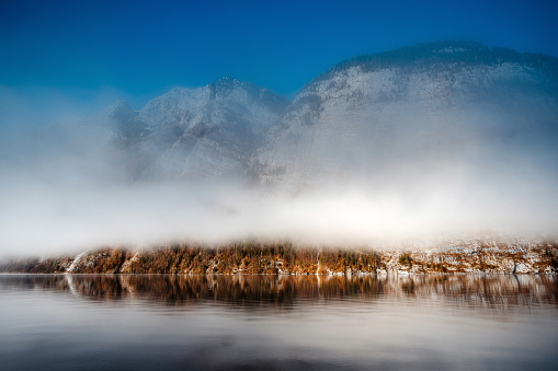 Picturesque view of frozen lake surrounded by hills under cloudy summer sky in national park. Stock photo