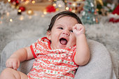 Happy newborn baby wearing Christmas clothes with decoration in the living room for Christmas and New Year's party at home.