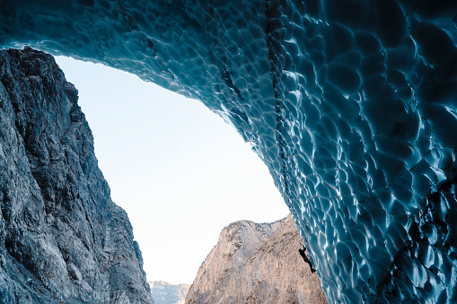 Male hiker climbing on textured surface of ice caves at national bavarian park. Active lifestyles, extreme and people concept.