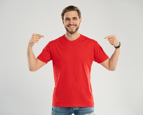 Clothes Template. Happy man pointing at red t-shirt, mockup for logo or branding design