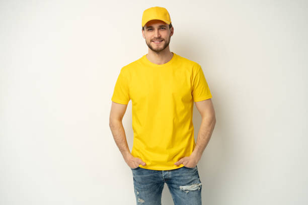istock Delivery man in yellow uniform isolated on white background. Professional smiling confident male employee in cap, t-shirt courier dealer 1804028020