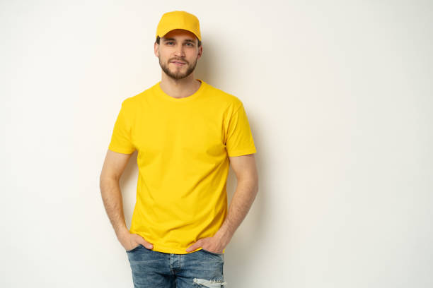 istock Delivery man in yellow uniform isolated on white background. Professional smiling confident male employee in cap, t-shirt courier dealer 1804028022