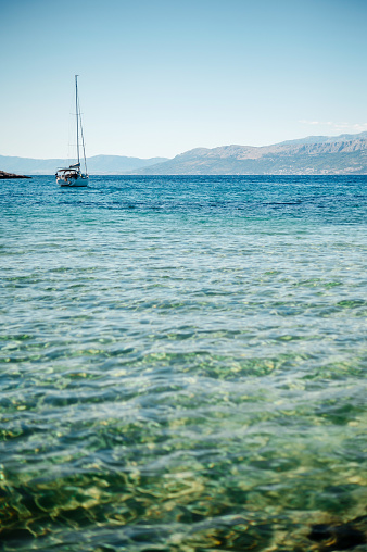 White tourist boat conducting tour on Adriatic sea with crystal clear water. High rocky mountains connecting with blue sky on background. Beautiful landscape in Croatia.