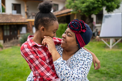 Portrait of an Afro-American mother looking at the eyes of her small daughter and smilng