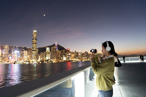 Woman admiring the night view of Victoria Harbor in Hong Kong