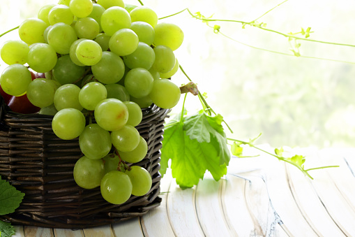 Fresh organic grapes in wooden bowl on rustic wooden table