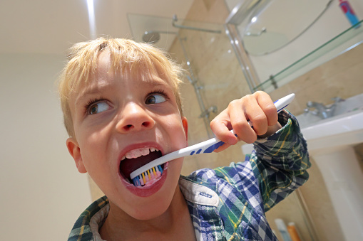Low angle view of young boy brushing teeth in pyjamas