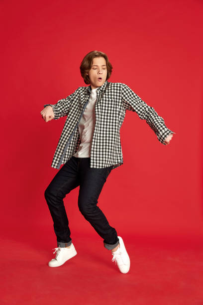 istock One young guy, student wearing casual style clothes dancing over red studio background with pleasure. Exam passed 1804113495