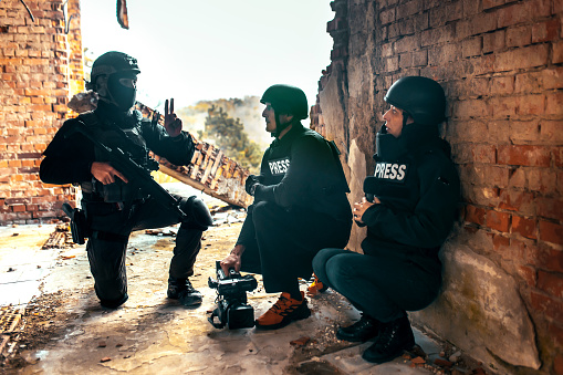 journalists in a war zone film soldiers and give an interview