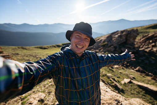 Selfie portrait of happy tourist man hiking in mountains. Space for text.