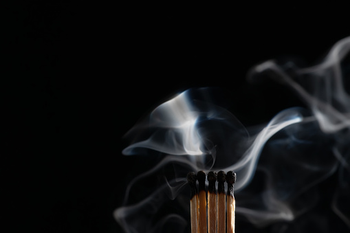 Ignition of matches with smoke, isolated on black background. Match just after burning