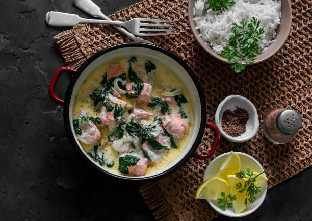 istock Delicious balanced served lunch - salmon spinach cream sauce stewed and basmati rice on a dark background, top view 1804120531